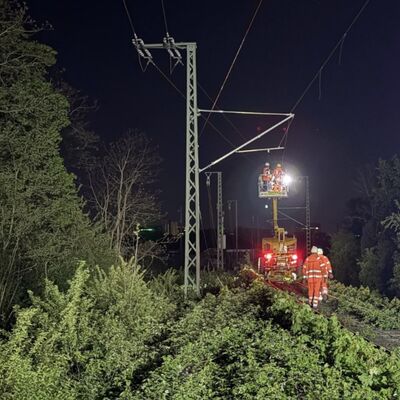 Personen führen in der Nacht Oberleitungsarbeiten durch.