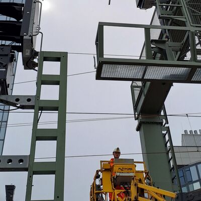 Ein Arbeiter im Kran, über ihm Signalausleger