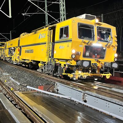 Eine Gleisstopfmaschine ist in der Nacht im Einsatz.
