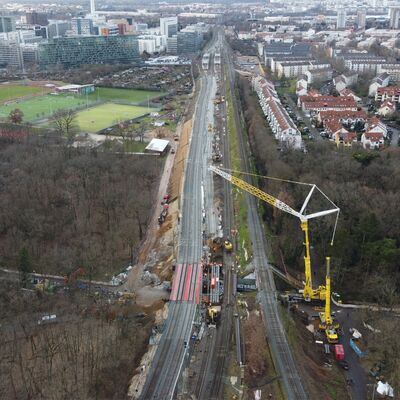 Drohnenaufnahme von Gleisen. Rechts steht ein gelber Kran.