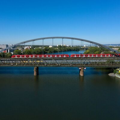 Über eine Eisenbahnbrücke fährt ein roter Zug.